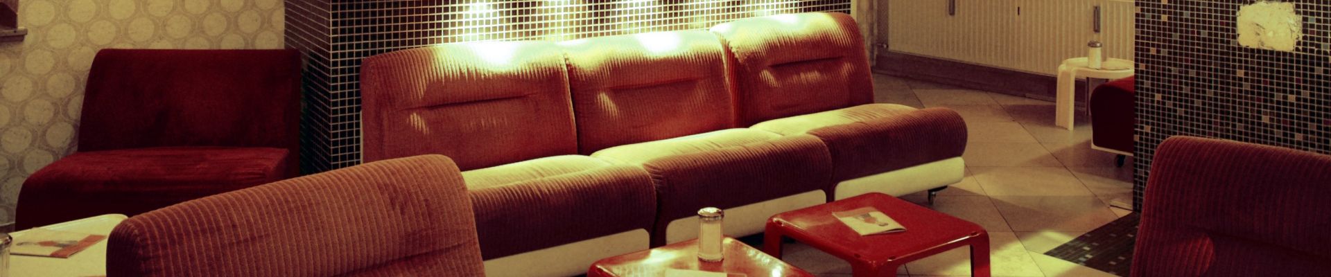 Originalfoto der Café-Franck-Lounge mit roten Sofas und Retro-Tapete
